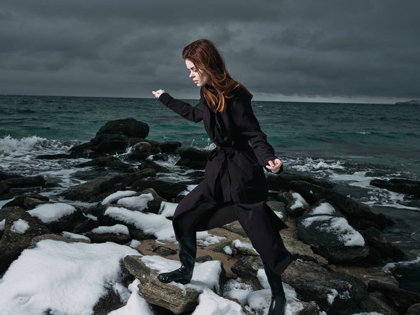 Frau in schwarzem Mantel draußen Landschaft Ozean dunkle Wolken gotische - Foto, Bild