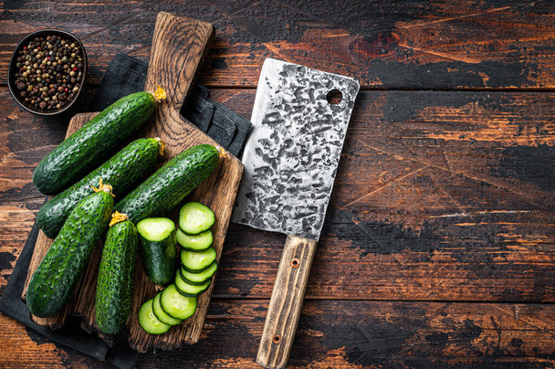 Sliced Green Cucumbers on a wooden cutting board. Dark Wooden background. Top view. Copy space - Foto, imagen