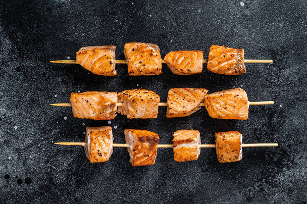 Grilled salmon kebab skewers. Black background. Top View - Photo, Image