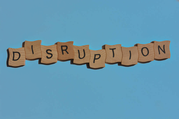 Disruption, word in wooden alphabet letters isolated on blue background as banner headline with effects added - Photo, Image