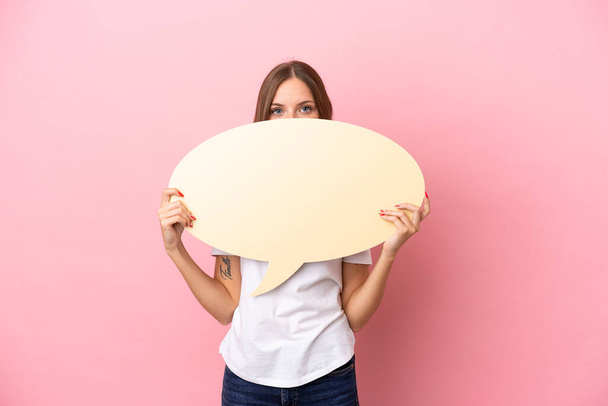 Young Lithuanian woman isolated on pink background holding an empty speech bubble hiding behind it hiding behind it - Fotoğraf, Görsel