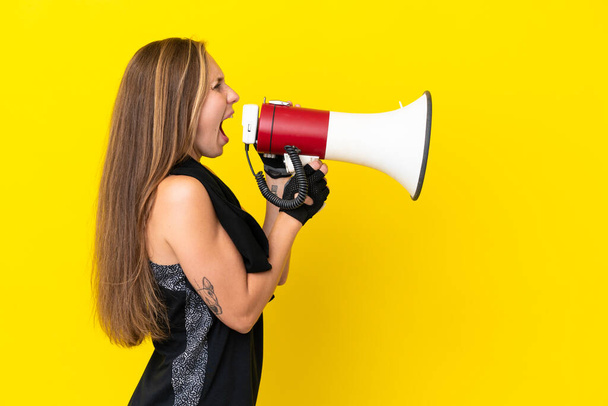 Young sport English woman isolated on white background shouting through a megaphone - Фото, изображение