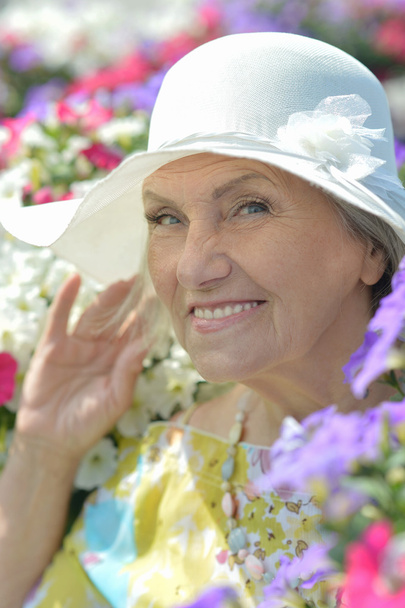 Happy older woman smiling with flowers - Foto, Bild