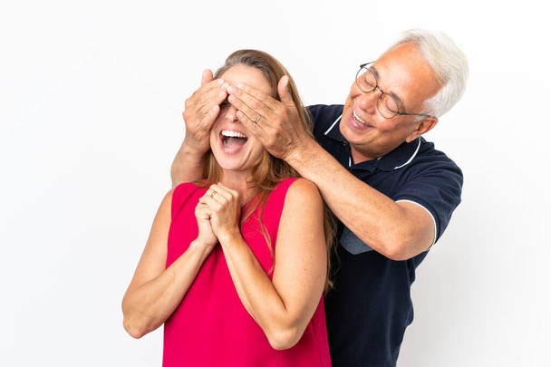 Middle age couple isolated on white background covering his eyes to surprise him - Zdjęcie, obraz