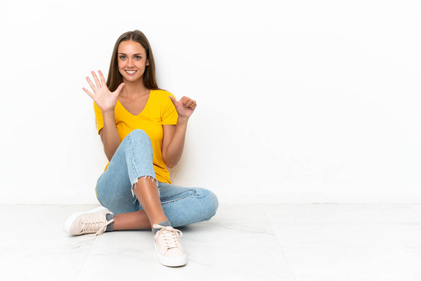 Jeune fille assise sur le sol comptant six avec les doigts
 - Photo, image