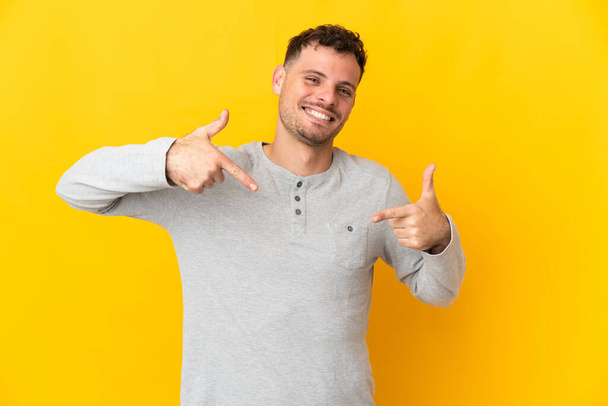 Young caucasian handsome man isolated on yellow background proud and self-satisfied - Фото, зображення