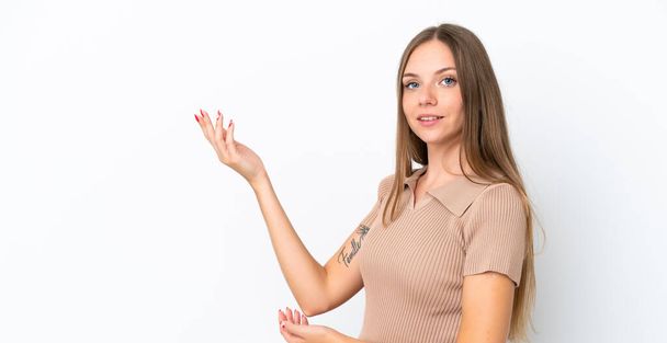 Genç Litvanyalı bir kadın beyaz arka planda izole edilmiş, davet edilmek için ellerini yana uzatıyor. - Fotoğraf, Görsel