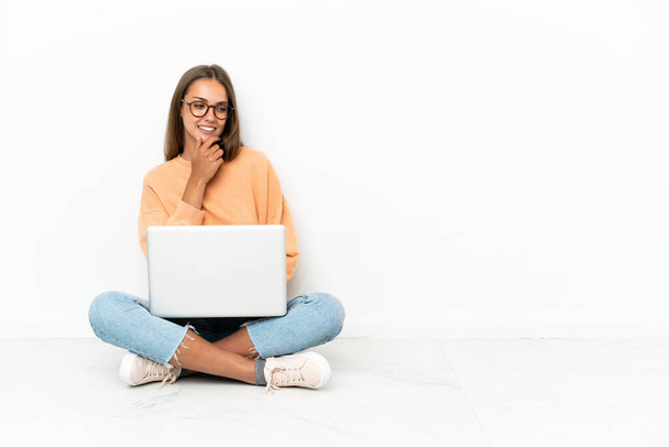 Young woman with a laptop sitting on the floor looking to the side - Foto, Imagem