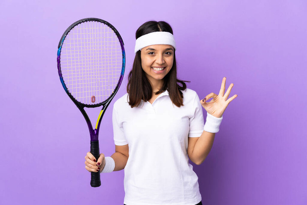 Młoda kobieta tenisistka na odosobnionym tle pokazuje znak ok palcami - Zdjęcie, obraz