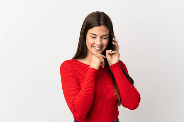 Teenager Brazilian girl using mobile phone over isolated white background looking to the side and smiling - Φωτογραφία, εικόνα