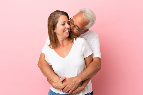 Couple d'âge moyen isolé sur fond rose étreinte - Photo, image
