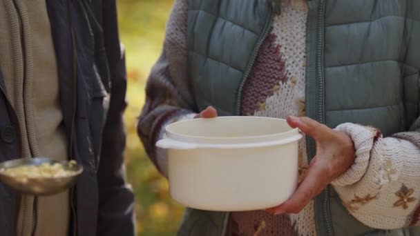 Jótékonysági est. Idős nő meleg ételt kap. Zárja le a műanyag tartályt - Felvétel, videó