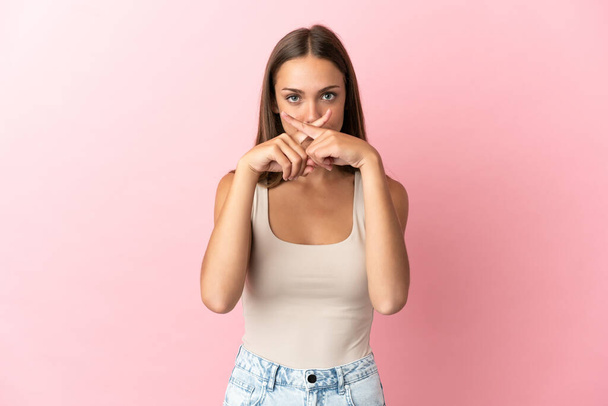 Mladá žena nad izolované růžové pozadí ukazující znamení mlčení gesto - Fotografie, Obrázek