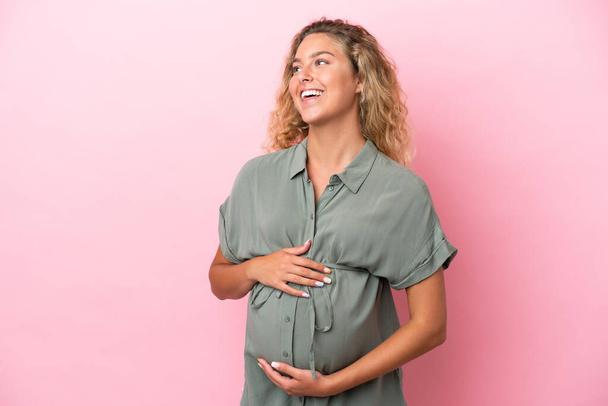 Girl with curly hair isolated on pink background pregnant and happy - Foto, Imagem