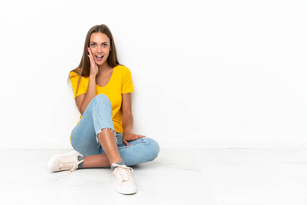 Young girl sitting on the floor with surprise and shocked facial expression - Foto, Bild