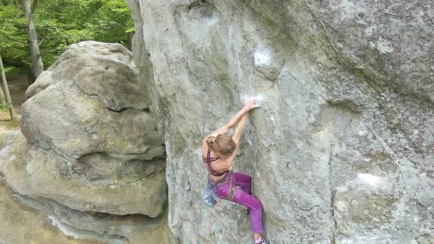 Vastberaden meisje klimmer klauteren omhoog steile muur van rotsachtige berg. Sportvrouw overwint moeilijke route. Betrokken bij extreme sporten en rotsklimmen hobby concept. - Video
