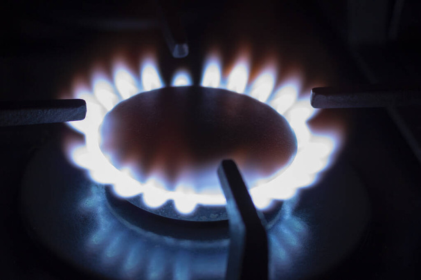 A chama azul do gás natural no escuro. Um queimador de gás em chamas no fogão da cozinha. - Foto, Imagem