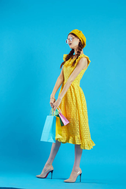 smiling woman in a yellow hat Shopaholic fashion style blue background - Fotoğraf, Görsel