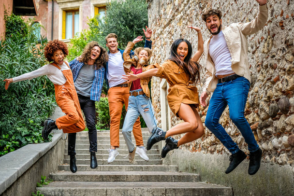 Multi-ethnische Gruppe verrückter junger Leute, die die Treppe in der Stadtstraße hinunterspringen und Spaß haben - Urban concept - Foto, Bild
