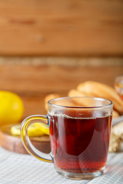 A cup of strong infused tea on a napkin next to lemon ginger. Vertical photo - Foto, imagen