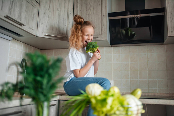 Little girl the kitchen. Green fresh vegetables and salad, healthy food - Foto, afbeelding