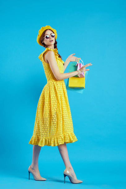 smiling woman in a yellow hat Shopaholic fashion style blue background - Valokuva, kuva