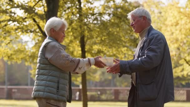 Öregasszony önkéntes ingyen ételt ad idős férfinak. Jótékonyság és szociális jólét - Felvétel, videó