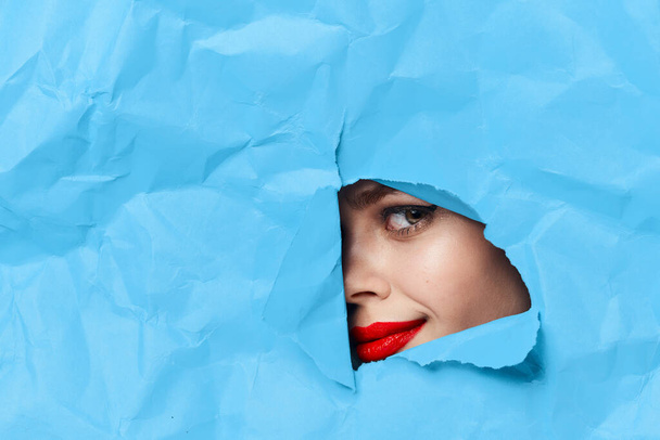 womans face breaks through blue mockup close-up - Foto, afbeelding