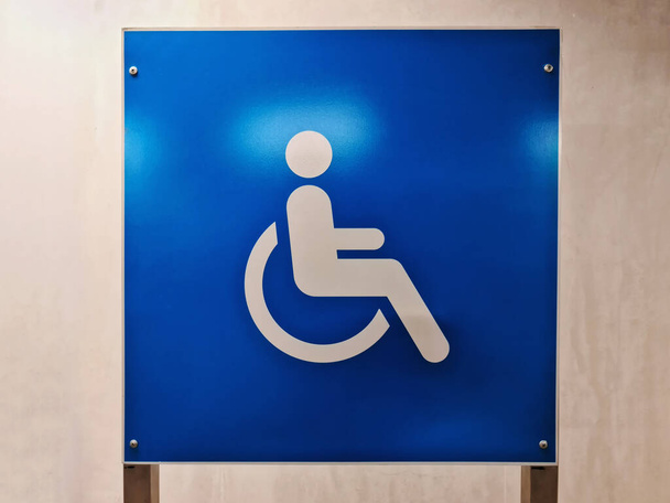Biały Handicap Parking Znak na niebieskiej płycie pod ścianą - Zdjęcie, obraz