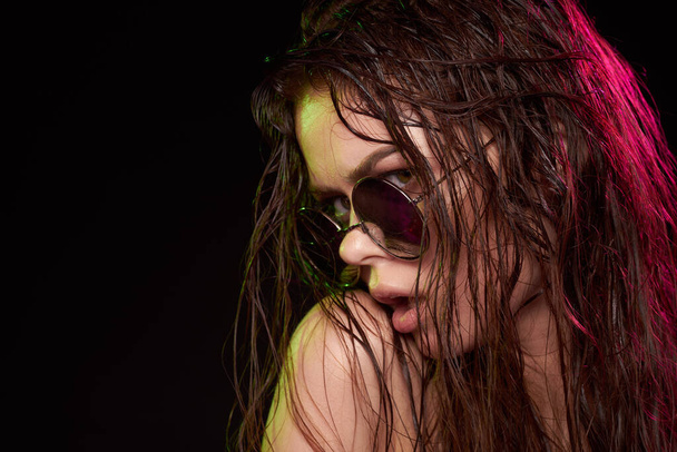 portrait of a woman wearing sunglasses posing luxury dark background - Foto, Imagen