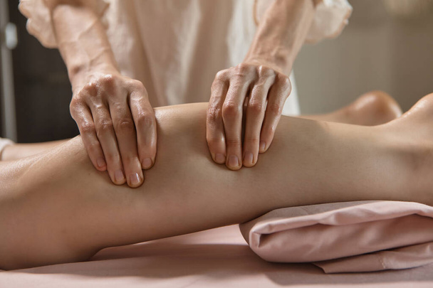 Масаж ніг крупним планом. Професійний терапевт, який дає масаж м'язів теляти жінці в спа-центрі. Жіночий масажист масажує ноги клієнтів. Релаксація тіла та догляд за шкірою
 - Фото, зображення