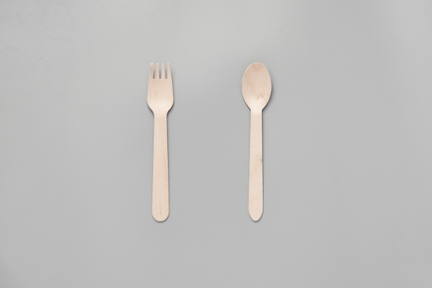 Wooden spoon, fork, paper cups gray background. Disposable tableware made of natural materials. The concept of a zero waste, sustainable lifestyle. Eco-friendly disposable tableware - Фото, изображение