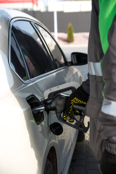 Um funcionário do posto de gasolina enche um carro em um posto de gasolina - Foto, Imagem