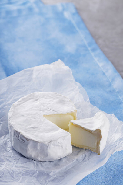 Camembert cheese on blue napkin. White cheese on cement surface. Copy space - Photo, image