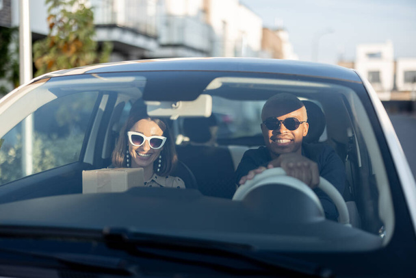 Multiracial couple riding in car at sunny day - Φωτογραφία, εικόνα