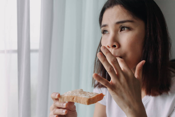 Woman eat bread with sweetened condensed milk as easy breakfast. - 写真・画像