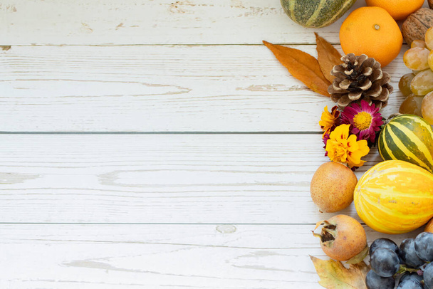 Top view of white wooden background with fall fruits (pumpkins, grapes, tangerines, medlars, flowers, and leaves). The concept of thanksgiving and thankfulness to God Jesus Christ. Copy space. - Photo, Image
