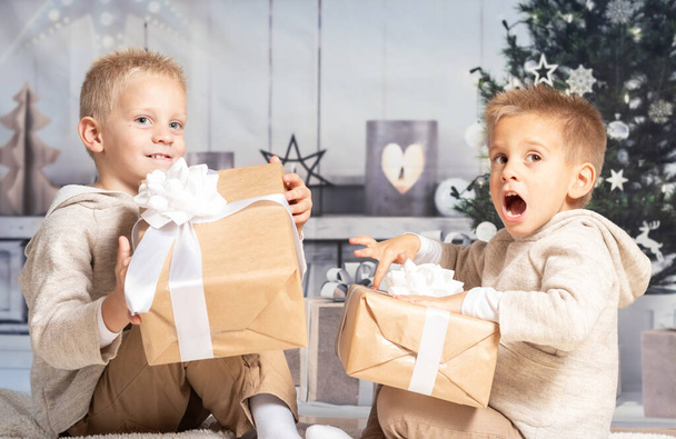 Twin children at home receiving and opening Christmas presents. - 写真・画像