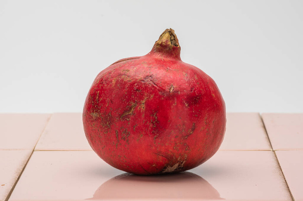 pomegranate on pink tile - Zdjęcie, obraz