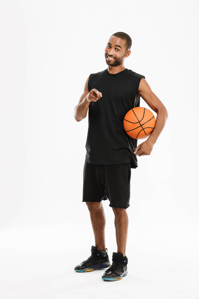 Young black sportsman pointing finger at camera while posing with basketball isolated over white background - Фото, зображення