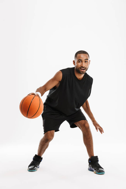Young black sportsman playing basketball while working out isolated over white background - Fotó, kép