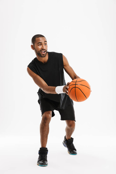Young black sportsman playing basketball while working out isolated over white background - Zdjęcie, obraz