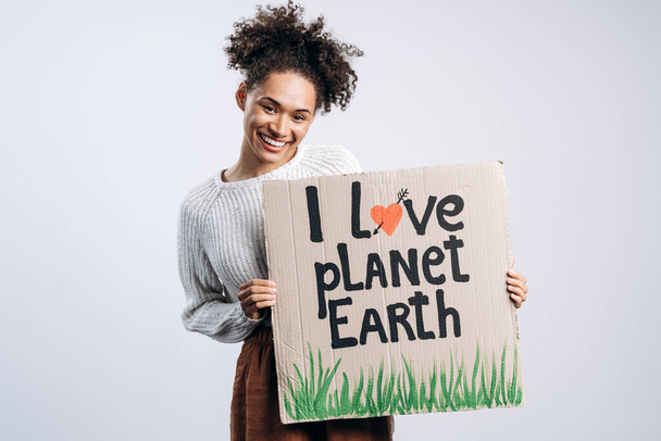Multiracionális vidám nő kartondobozos plakáttal a kezében. Imádom a Föld bolygót írni. A természetpusztítás és az ökoaktivizmus fogalma - Fotó, kép
