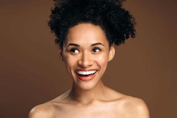 Portrait view of young charming multiracial lady with perfect skin standing and looking away with happy emotion in studio. Beauty, facial treatment and spa concept - Fotoğraf, Görsel