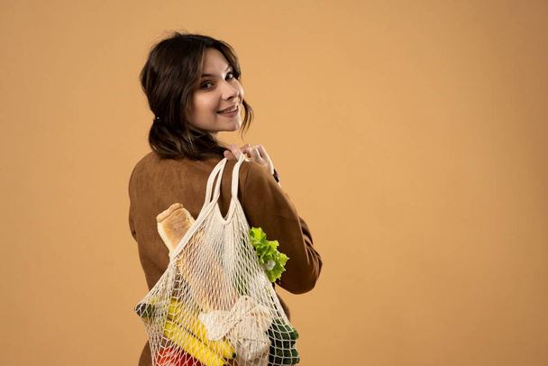 Zero waste concept. Young woman holding reusable cotton shopping mesh bag with groceries from a market. Concept of no plastic. Zero waste, plastic free. Eco friendly concept. Sustainable lifestyle. - Foto, imagen