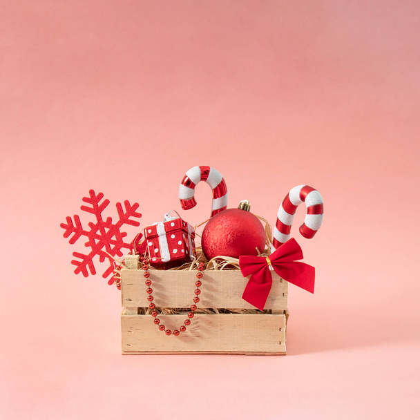 Panier de Noël créatif vintage plein de décoration rouge. Sucette, flocon de neige, cadeau, balle et ruban. Fond rose. - Photo, image