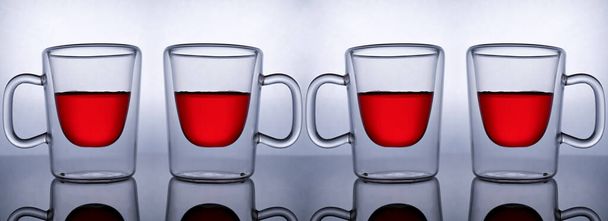 Διαφανές ποτήρι κύπελλα με κόκκινο χυμό ροδιού, απομονώνονται σε φωτεινό ανακλαστικό φόντο, web banner - Φωτογραφία, εικόνα
