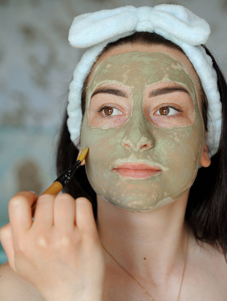 Mulher faz tratamentos de beleza, aplica esfoliação em seu rosto.  - Foto, Imagem