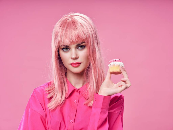 ケーキとヘアスタイルのモデルピンクの背景を持つシャツの女性 - 写真・画像