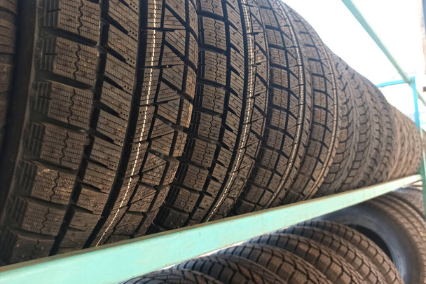 Muchos neumáticos de goma negro del coche en estante de la tienda para la venta. - Foto, imagen